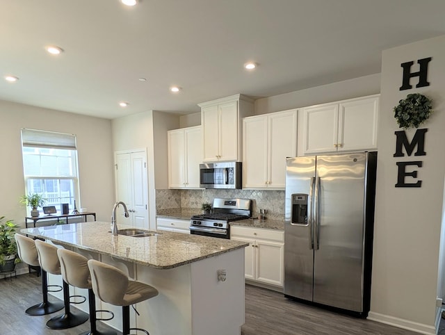 63 Nicholas Dr W, Des Plaines, IL 60016 - kitchen featuring stainless steel appliances, dark wood finished floors, an island with sink, tasteful backsplash, and light stone countertops
