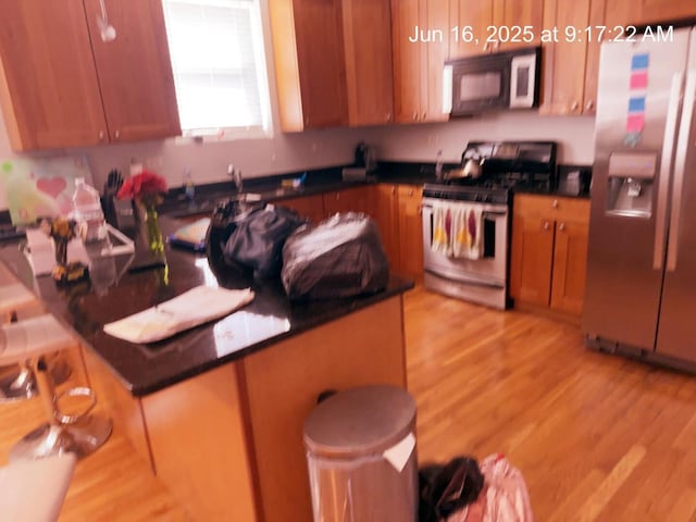 2651 E 74th St Unit 201, Chicago, IL 60649 - kitchen featuring appliances with stainless steel finishes, light wood-type flooring, dark countertops, and brown cabinetry
