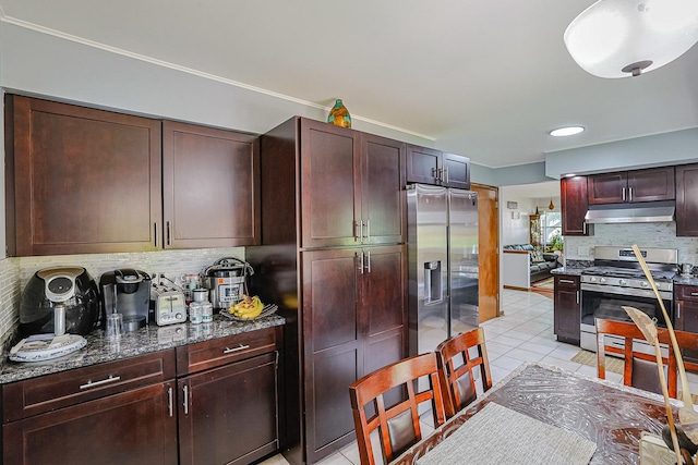 1008 S Beechwood Dr, Mount Prospect, IL 60056 - kitchen with stainless steel appliances, under cabinet range hood, decorative backsplash, light tile patterned floors, and dark stone countertops