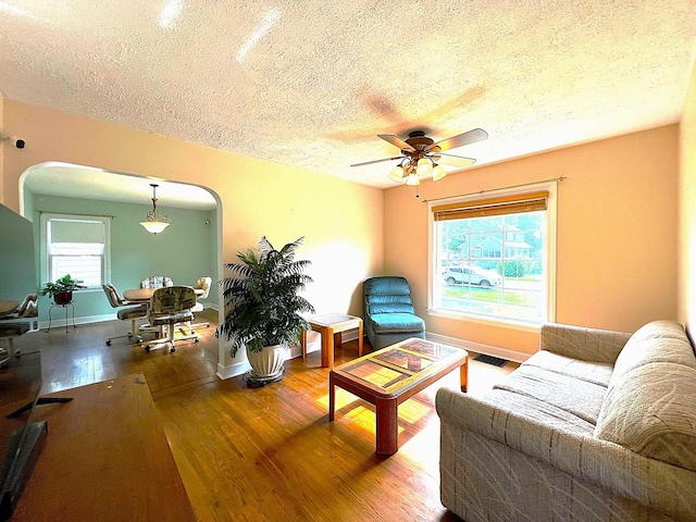 4225 Highland Ave, Downers Grove, IL 60515 - living area featuring a textured ceiling, arched walkways, wood finished floors, a ceiling fan, and plenty of natural light