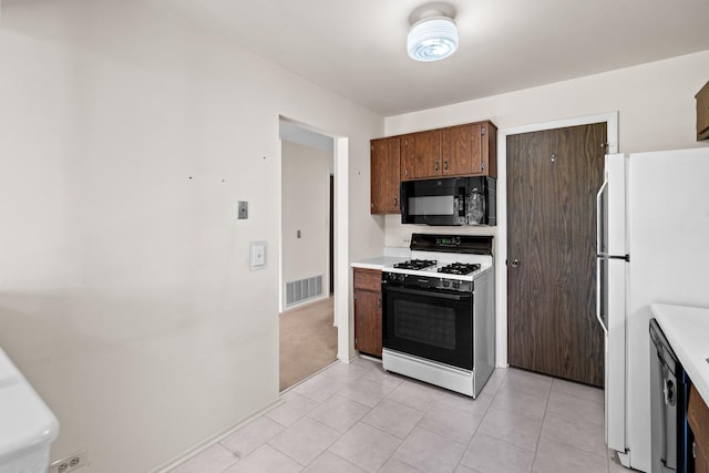 543 Williamsburg Ct Unit C2, Wheeling, IL 60090 - kitchen featuring range with gas stovetop, black microwave, freestanding refrigerator, light countertops, and light tile patterned floors