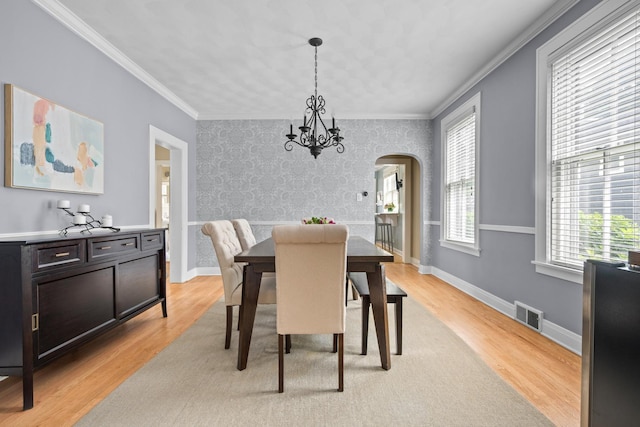1718 Lake Ave, Wilmette, IL 60091 - dining room with arched walkways, light wood-style floors, a chandelier, crown molding, and wallpapered walls