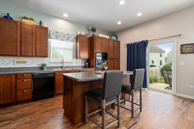 8102 Expedition St, Joliet, IL 60431 - kitchen featuring black appliances, a kitchen breakfast bar, tasteful backsplash, dark wood-style floors, and recessed lighting