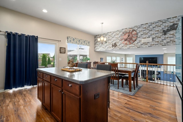 8102 Expedition St, Joliet, IL 60431 - kitchen featuring wood finished floors, a kitchen island, a chandelier, decorative light fixtures, and plenty of natural light