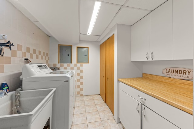 3812 N Pioneer Ave, Chicago, IL 60634 - laundry room with cabinet space, electric panel, washing machine and clothes dryer, tile walls, and light tile patterned floors