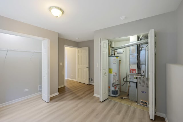 64 Village Station Ln, Grayslake, IL 60030 - unfurnished bedroom with gas water heater, light wood finished floors, and heating unit
