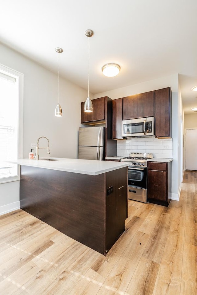 2244 S Sawyer Ave, Chicago, IL 60623 - kitchen featuring appliances with stainless steel finishes, dark brown cabinetry, light wood-style floors, backsplash, and light countertops