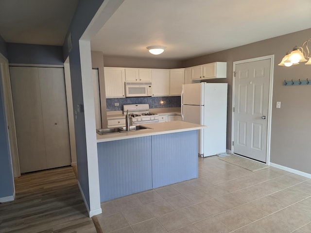 415 Andrea Ct, Harvard, IL 60033 - kitchen featuring white appliances, a peninsula, light countertops, white cabinetry, and decorative backsplash