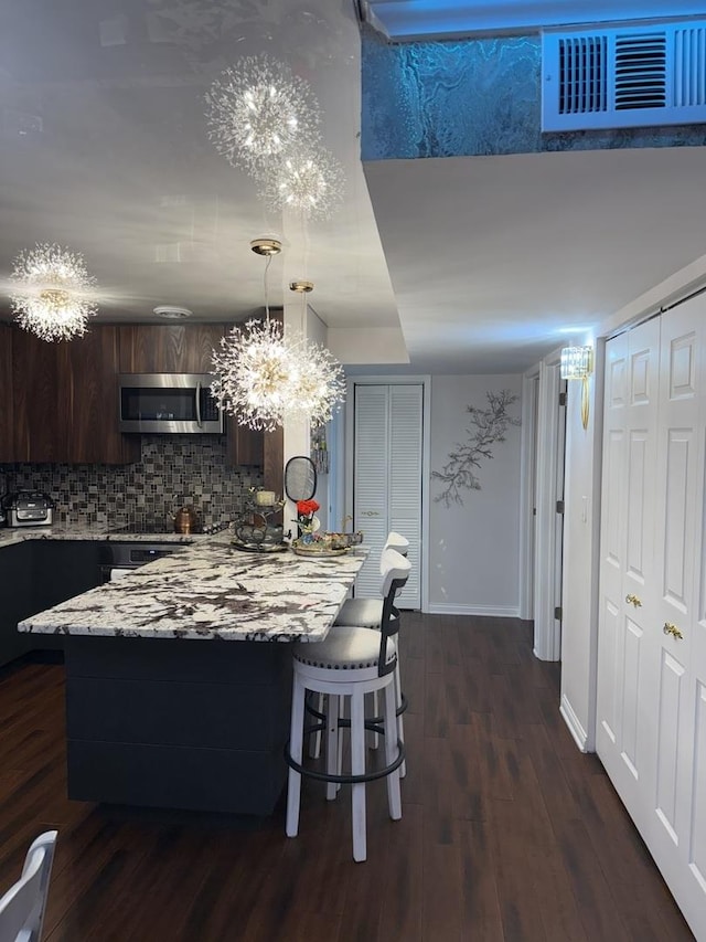 11A Kingery Quarter Unit 202, Willowbrook, IL 60527 - kitchen featuring stainless steel microwave, dark brown cabinetry, backsplash, dark wood-style flooring, and a chandelier