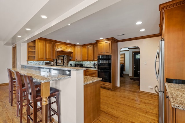 6759 W 91st St, Oak Lawn, IL 60453 - kitchen featuring open shelves, a peninsula, arched walkways, brown cabinets, and light wood-style floors