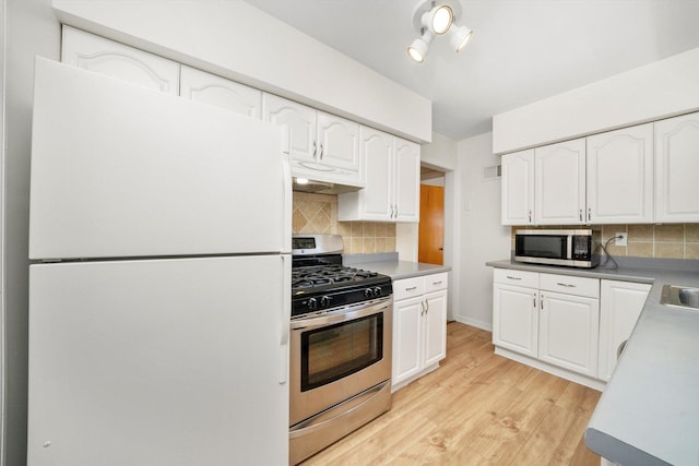5145 Lee St, Skokie, IL 60077 - kitchen with appliances with stainless steel finishes, under cabinet range hood, light wood-style floors, white cabinets, and backsplash