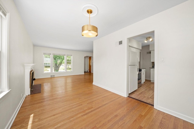 5145 Lee St, Skokie, IL 60077 - unfurnished living room with arched walkways, light wood-style floors, and a fireplace with flush hearth