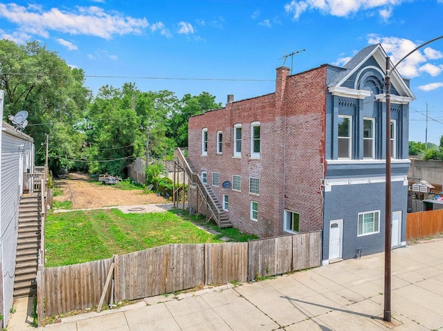 396 E Kensington Ave, Chicago, IL 60628 - view of side of home with stairway, a fenced backyard, a patio area, and brick siding
