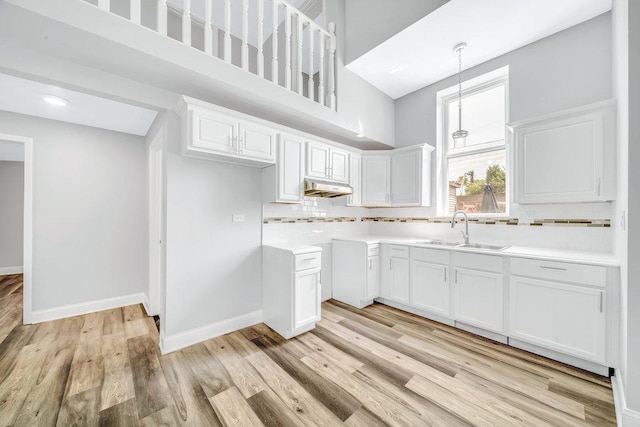 396 E Kensington Ave, Chicago, IL 60628 - kitchen featuring under cabinet range hood, backsplash, light wood-style flooring, white cabinetry, and a high ceiling