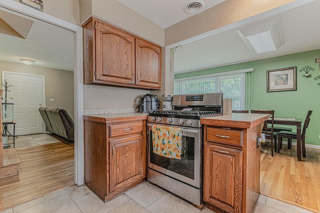 374 Heine Ave, Elgin, IL 60123 - kitchen with stainless steel gas range, light countertops, brown cabinets, and light tile patterned floors