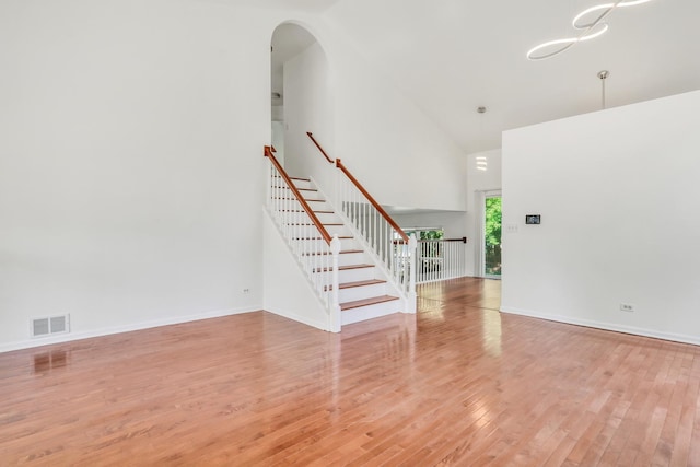 1379 Clavey Ln, Gurnee, IL 60031 - unfurnished living room with high vaulted ceiling, stairs, wood finished floors, and arched walkways