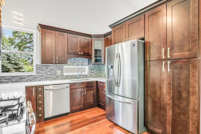 1379 Clavey Ln, Gurnee, IL 60031 - kitchen featuring stainless steel appliances, light wood finished floors, light countertops, tasteful backsplash, and glass insert cabinets