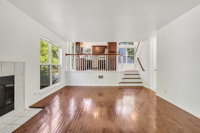 1379 Clavey Ln, Gurnee, IL 60031 - unfurnished living room with a tiled fireplace, plenty of natural light, stairway, and wood-type flooring