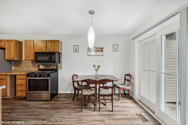 1340 Kingsbury Dr Unit 2, Hanover Park, IL 60133 - kitchen with black microwave, stainless steel gas range oven, dark wood finished floors, tasteful backsplash, and brown cabinetry
