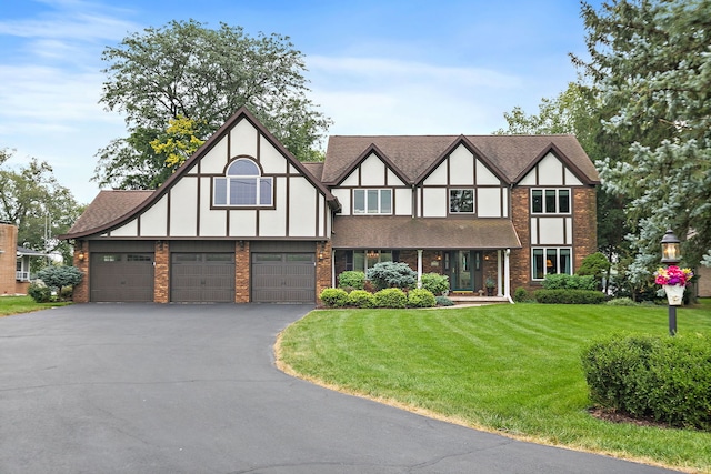 1606 Gregden Shores Dr, Sterling, IL 61081 - tudor home with asphalt driveway, a front lawn, brick siding, an attached garage, and a shingled roof