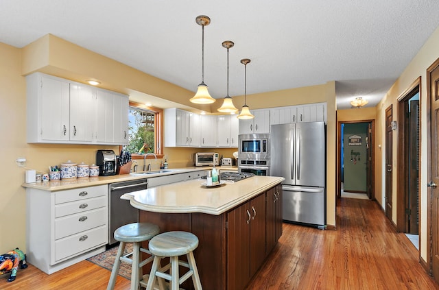 1606 Gregden Shores Dr, Sterling, IL 61081 - kitchen with stainless steel appliances, light countertops, wood finished floors, white cabinetry, and a center island