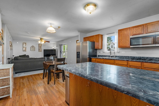 5505 Salma St, Plainfield, IL 60586 - kitchen featuring appliances with stainless steel finishes, brown cabinetry, light wood finished floors, and plenty of natural light