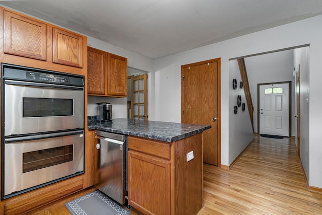 5505 Salma St, Plainfield, IL 60586 - kitchen with stainless steel appliances, a peninsula, light wood-type flooring, dark countertops, and brown cabinets