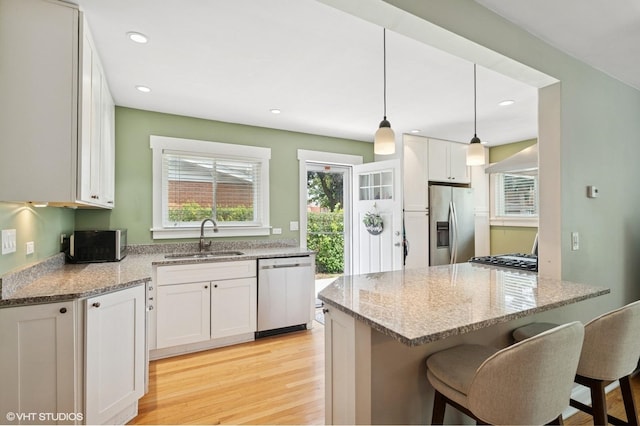1308 Hoffman Ave, Park Ridge, IL 60068 - kitchen with stainless steel appliances, light stone counters, light wood-type flooring, a breakfast bar, and white cabinets