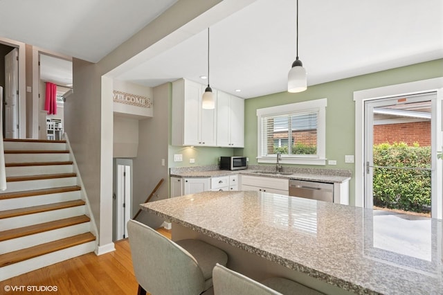 1308 Hoffman Ave, Park Ridge, IL 60068 - kitchen featuring appliances with stainless steel finishes, a breakfast bar area, light wood-type flooring, white cabinets, and plenty of natural light