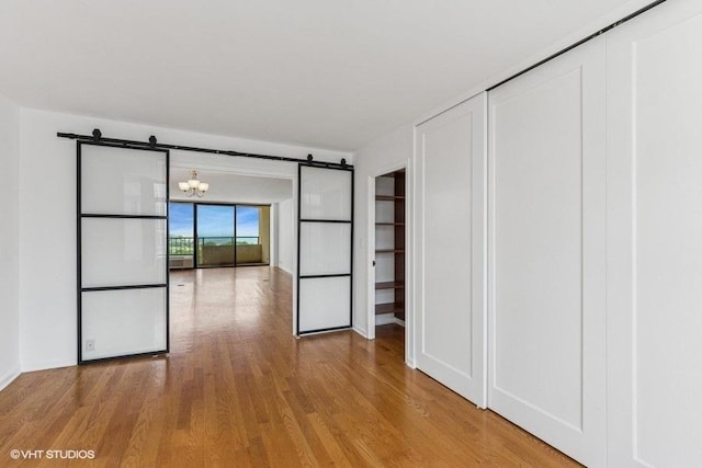 1450 N Astor St Unit 14D, Chicago, IL 60610 - unfurnished bedroom with a barn door, wood finished floors, a chandelier, and a closet