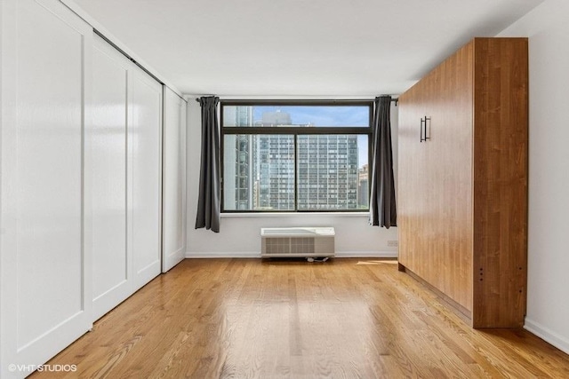 1450 N Astor St Unit 14D, Chicago, IL 60610 - unfurnished bedroom with wood finished floors, a wall mounted AC, and a closet