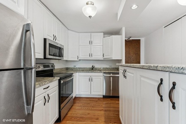 1450 N Astor St Unit 14D, Chicago, IL 60610 - kitchen with appliances with stainless steel finishes, white cabinetry, light stone countertops, wood finished floors, and recessed lighting