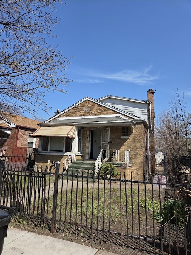 10511 S Yates Ave, Chicago, IL 60617 - bungalow featuring a chimney, a fenced front yard, brick siding, and covered porch