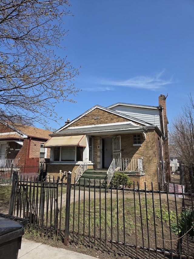 10511 S Yates Ave, Chicago, IL 60617 - bungalow-style home featuring brick siding, a chimney, a fenced front yard, and covered porch