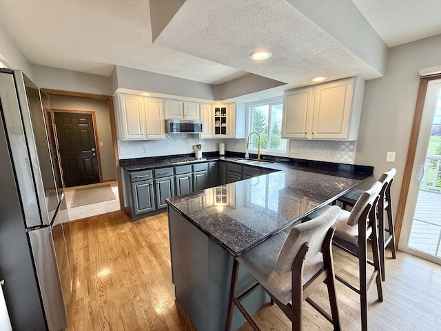 5448 S Branch Ct, Rochelle, IL 61068 - kitchen featuring stainless steel appliances, a peninsula, a kitchen bar, light wood-style flooring, and tasteful backsplash
