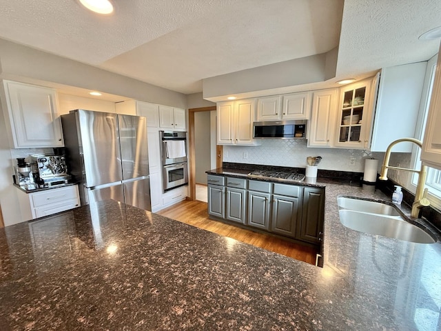 5448 S Branch Ct, Rochelle, IL 61068 - kitchen featuring appliances with stainless steel finishes, glass insert cabinets, decorative backsplash, light wood-type flooring, and a textured ceiling