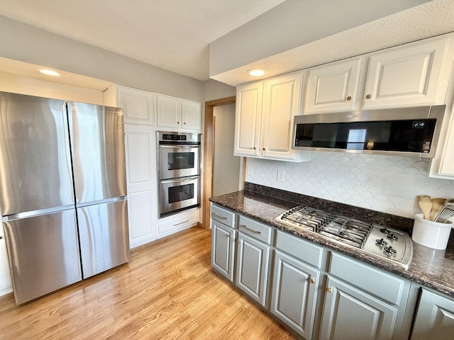5448 S Branch Ct, Rochelle, IL 61068 - kitchen featuring appliances with stainless steel finishes, white cabinetry, light wood-style flooring, dark stone countertops, and recessed lighting