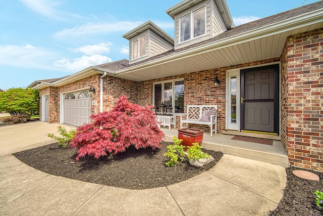207 Hamilton Ave, Frankfort, IL 60423 - view of exterior entry featuring a porch, an attached garage, concrete driveway, and brick siding