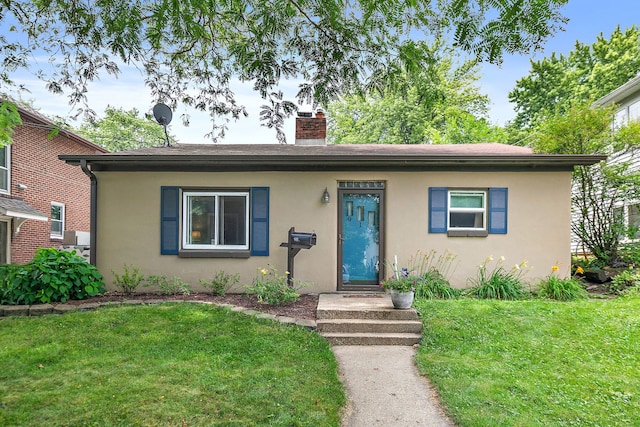 911 N 9th St, Dekalb, IL 60115 - view of front facade with stucco siding, a front lawn, and a chimney