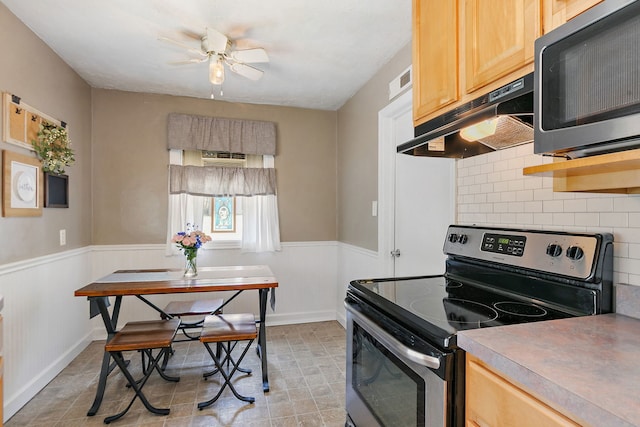 911 N 9th St, Dekalb, IL 60115 - kitchen featuring electric range, under cabinet range hood, light brown cabinets, a ceiling fan, and a wainscoted wall