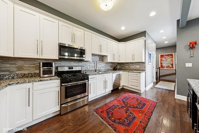 4229 S Prairie Ave, Chicago, IL 60653 - kitchen featuring stainless steel appliances, decorative backsplash, dark wood finished floors, light stone countertops, and white cabinets