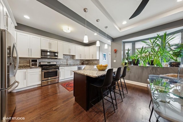 4229 S Prairie Ave, Chicago, IL 60653 - kitchen featuring stainless steel appliances, light stone countertops, decorative backsplash, white cabinets, and recessed lighting