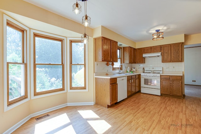 1021 Autumn Dr, Antioch, IL 60002 - kitchen with white appliances, under cabinet range hood, light wood finished floors, light countertops, and brown cabinets