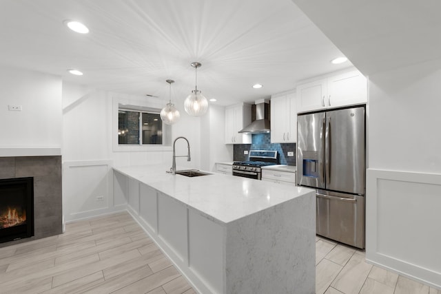 5312 S Woodlawn Ave Unit 1, Chicago, IL 60615 - kitchen featuring appliances with stainless steel finishes, white cabinetry, wall chimney range hood, a peninsula, and a tiled fireplace