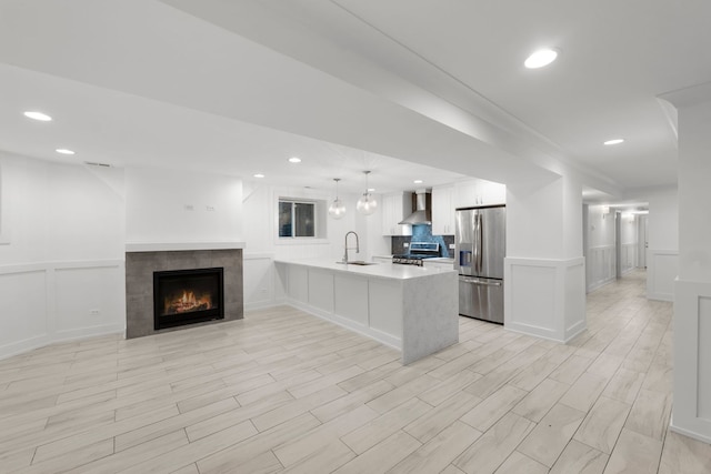 5312 S Woodlawn Ave Unit 1, Chicago, IL 60615 - kitchen with appliances with stainless steel finishes, wall chimney exhaust hood, a decorative wall, a peninsula, and light countertops