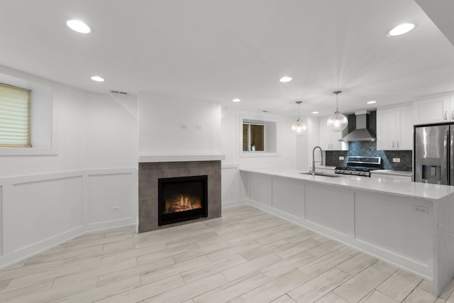 5312 S Woodlawn Ave Unit 1, Chicago, IL 60615 - kitchen with wall chimney range hood, stainless steel appliances, a decorative wall, recessed lighting, and a fireplace