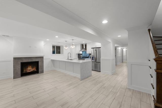 5312 S Woodlawn Ave Unit 1, Chicago, IL 60615 - kitchen featuring stainless steel appliances, wall chimney range hood, a peninsula, light countertops, and white cabinetry