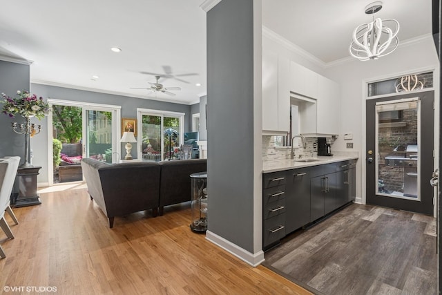 2848 N Burling St Unit 1, Chicago, IL 60657 - kitchen with ornamental molding, light countertops, backsplash, a ceiling fan, and white cabinets