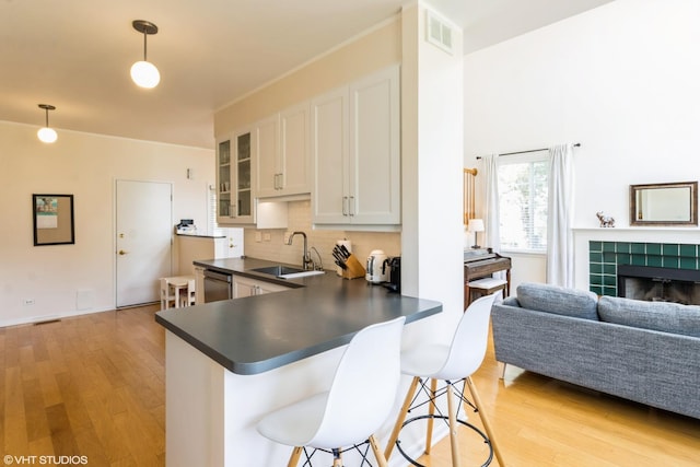 253 Sierra Pass, Schaumburg, IL 60194 - kitchen with dark countertops, light wood-style floors, stainless steel dishwasher, a breakfast bar, and glass insert cabinets