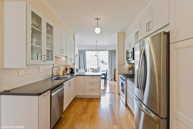 253 Sierra Pass, Schaumburg, IL 60194 - kitchen featuring appliances with stainless steel finishes, dark countertops, a peninsula, decorative backsplash, and light wood-style floors